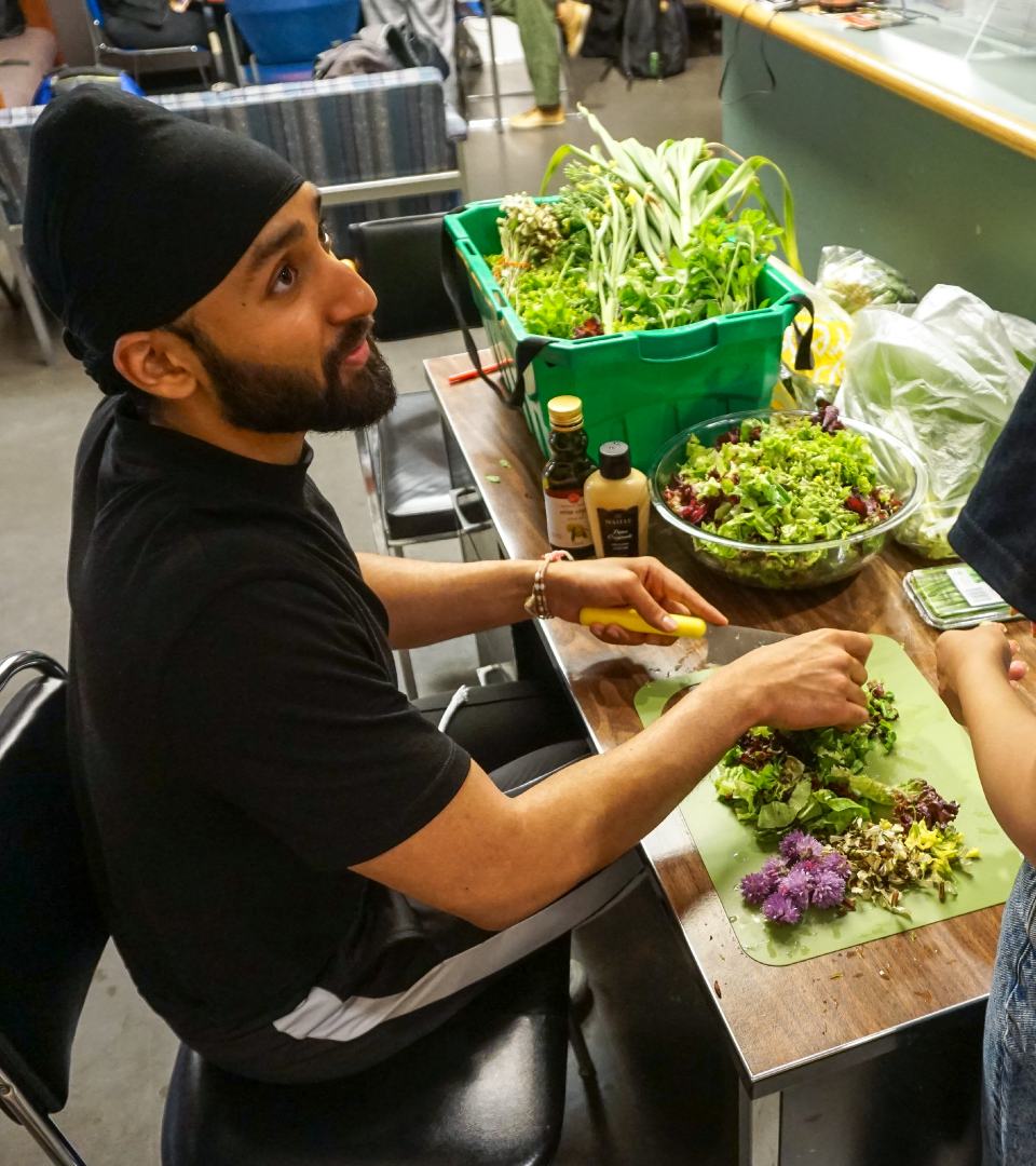 A person sits as they chop vegetables on a cutting board.